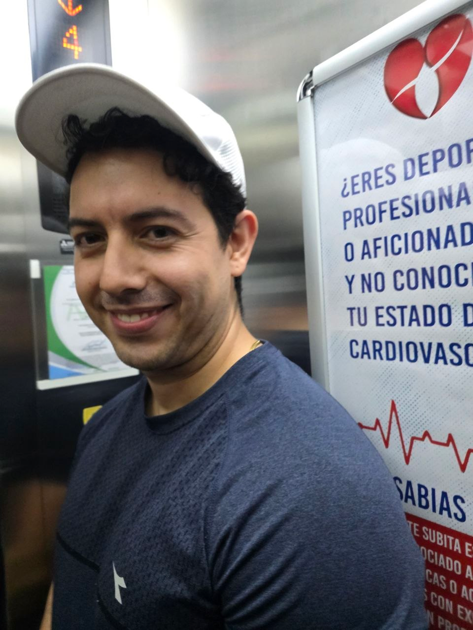 Selfie de un integrante con gorra blanca dentro de un ascensor.
